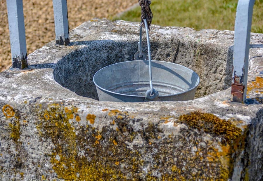Put-zandstenen-put-met-ijzeren-hengsel-en-katrol-waar-emmer-aan-hangt